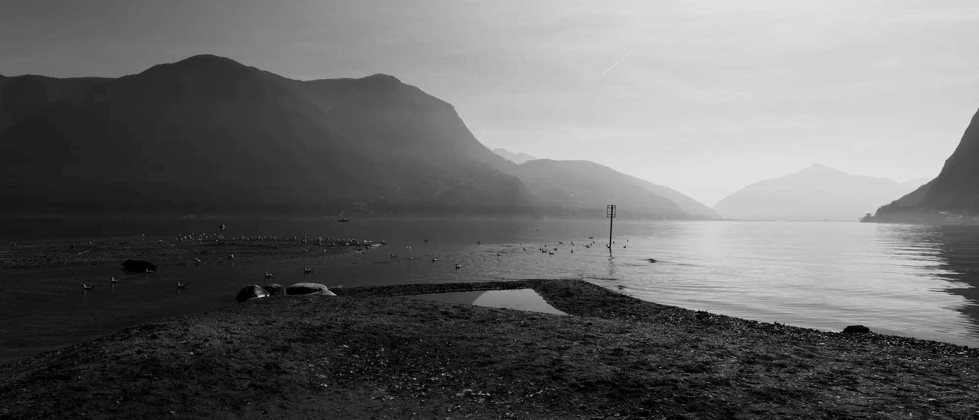 Il lago in bianco e nero, le montagne una dietro l'altra nella foschia