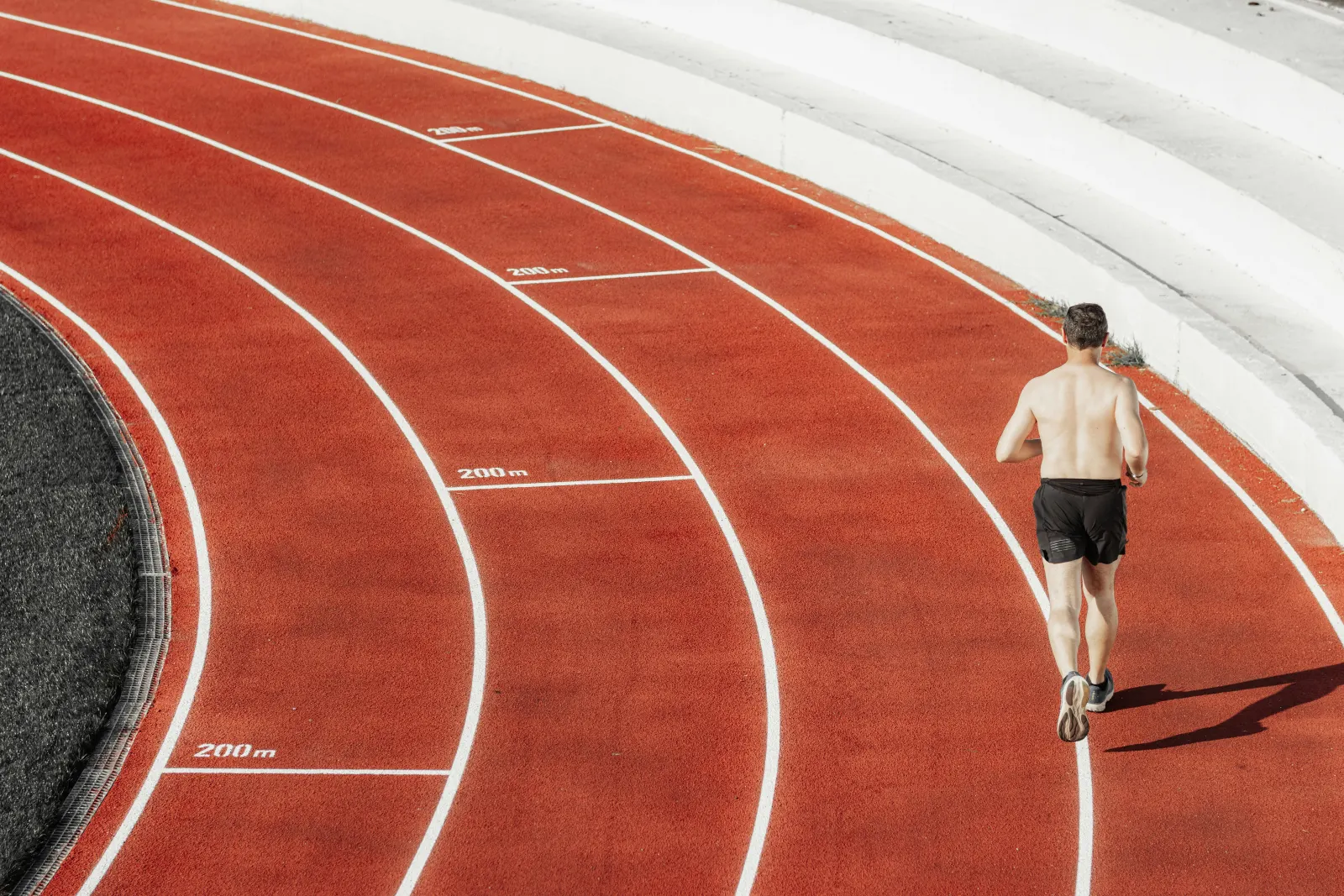 Un atleta in corsa su una pista rossa